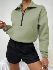 Detailansicht der Kängurutasche und des Reißverschlusses an einem grünen Sweatshirt.