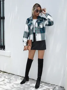 Full body shot of a stylish woman wearing a blue and white plaid shacket jacket with tall boots