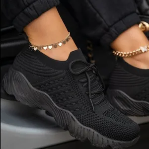 Gros plan de baskets noires en maille à semelles épaisses portées par un mannequin.