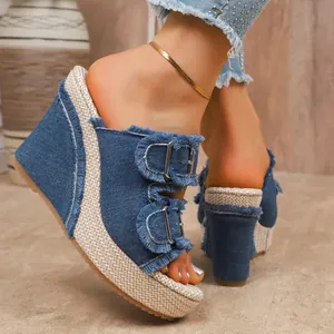 Macro detail view of stylish blue denim wedge platform sandals with fringe and buckles