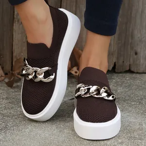 Close-up of women's brown fly-knit loafers with chunky gold chain decoration