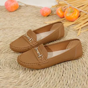 Close-up of brown women's loafers with metal buckle and perforated leather detail