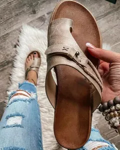 Primer plano de elegantes sandalias planas retro con hebilla en el dedo y tiras trenzadas oro
