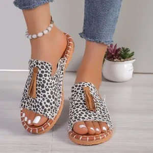 Close-up detail of dalmatian print peep-toe flat slippers with stylish tan tassels