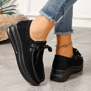 Vue détaillée de mocassins noirs à plateforme en daim avec surpiqûres blanches.