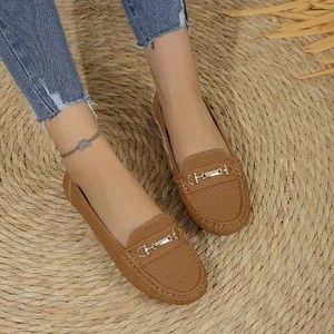 Detailed view of comfortable brown perforated loafers with metal buckle on a woven rug