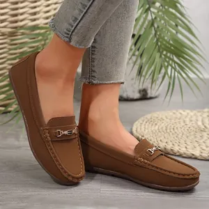 Detailed view of stylish brown women's loafers with a decorative metallic buckle on feet