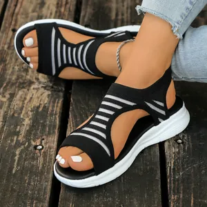 Close-up macro view of black and white striped knitted wedge sandals on a wooden deck