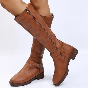 Close-up of brown faux leather knee-high boots with side zipper and buckle detail