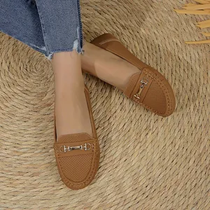 Detail view of brown women's loafers with metal bit detail on a woven straw mat