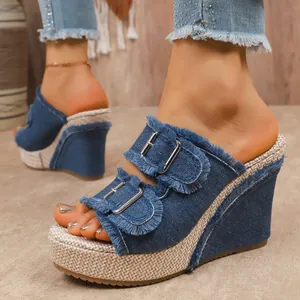 Close-up of fashionable denim wedge mules with frayed edges and double metal buckles