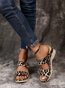 Close-up of retro leopard print wedge sandals with floral detail on model's feet
