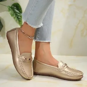 Close-up of stylish gold metallic women's loafers on model feet with casual denim jeans
