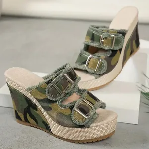 Close-up of camouflage denim wedge sandals with fringe edges and metallic buckles