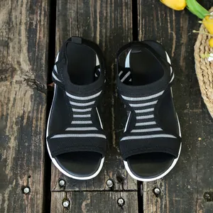 Top view of breathable black knit wedge sandals with white stripes on rustic wood surface