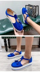 Stylish royal blue suede platform sandals with gold tassel detail and T-strap on model.