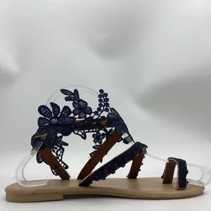 Detail view of navy blue lace floral pattern toe-loop flat sandals for summer beach vacation