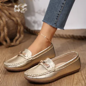 Stylish close-up of golden metallic loafers with buckle detail on rustic wooden floor