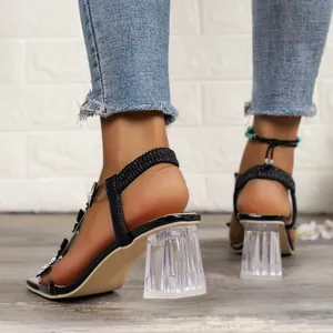 Detail view of women's sandals featuring clear crystal block heels and elastic straps