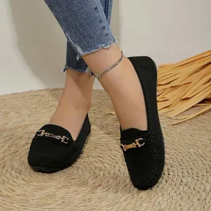 Close-up of stylish black loafers featuring a gold buckle on a natural woven mat