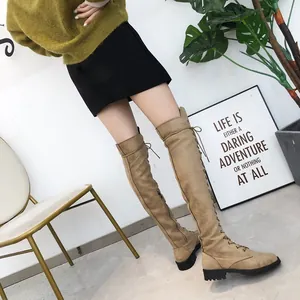 Side view of khaki lace-up over-the-knee boots on model in lifestyle setting