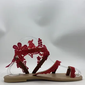 Macro detail of elegant red floral lace toe-loop flat sandals for beach vacation