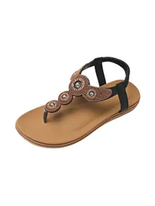 Bohemian flat T-strap sandals with intricate beadwork and rhinestones on black straps.