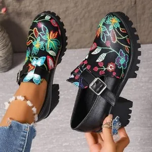 Detailansicht schwarzer Loafer mit Blockabsatz, Blumenstickerei und Riemenschnalle.