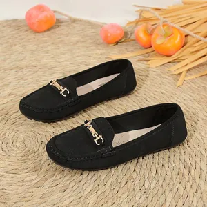 Close-up of stylish black loafers with gold metal buckle and perforated side detail