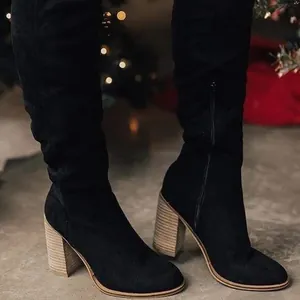 Detailed view of stylish black suede over-the-knee boots featuring chunky wooden heels.