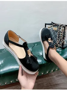 Detailed view of black suede platform sandals with gold tassel accents and T-strap