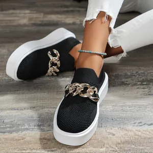 Detail of black breathable knit platform shoe with chunky gold chain ornament.