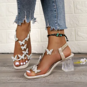Close-up of elegant square toe sandals with sparkling butterfly rhinestones and crystal heel.
