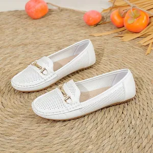 White perforated women's loafers featuring an elegant gold buckle on a flat sole