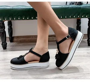 Close-up side view of black tassel platform sandals with T-strap and golden buckle