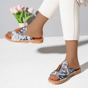 Close-up view of stylish blue floral pattern flat sandals with decorative brown tassels