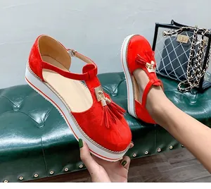 Close-up of red suede T-strap shoes with metallic accents and stylish tassel details