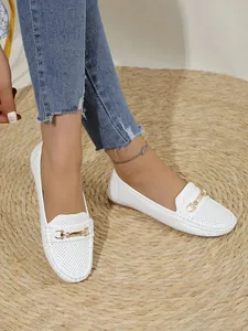 Detail shot of white women's loafers featuring perforated leather and gold bit buckle