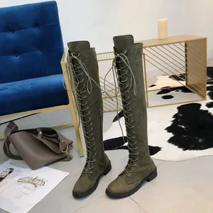 Detail view of olive green faux suede lace-up over-the-knee boots in a stylish home setting