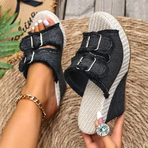 Close-up of stylish black denim wedge sandals featuring metal buckles and fringed details