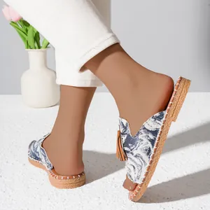 Detailed view of fashionable flat beach sandals with blue patterned upper and tassel