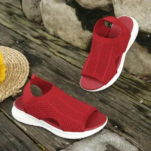 Breathable red fly-knit women's sandals with thick white soles in a natural outdoor setting