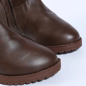Close-up detail of brown faux leather boots showing textured toe and durable sole