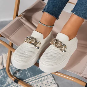 Close-up shot of white fly-knit platform loafers featuring a chunky gold chain detail
