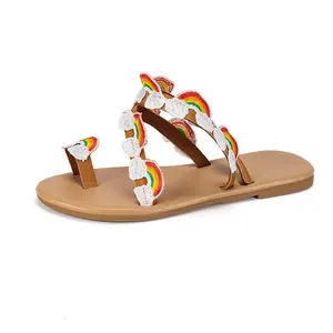 Detailed view of bohemian flat sandals with rainbow and cloud embroidery accents