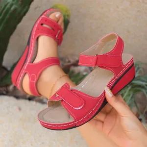 Primo piano di sandali con zeppa rossi rétro da donna con cuciture bianche e velcro