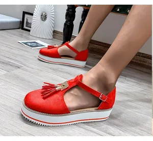 Detailed view of red faux suede platform sandals featuring tassels and gold buckle straps.