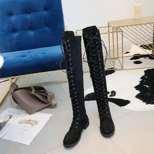 Black suede-like lace-up over-the-knee boots displayed in a stylish modern room