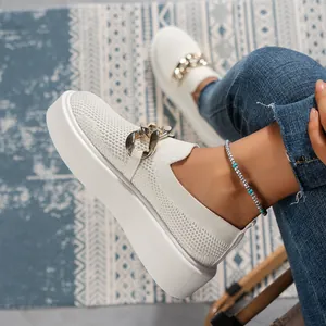 Close-up of white fly-knit platform loafers with decorative gold chain detail