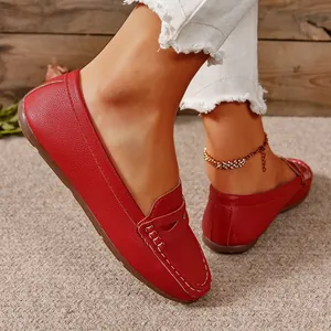 Close-up view of stylish red leather loafers with white stitching on a textured carpet